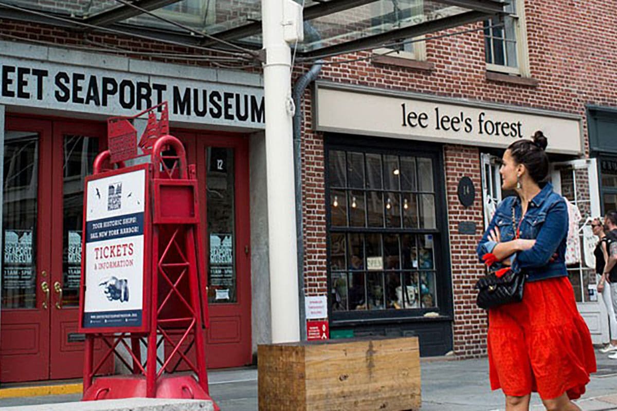 woman window shopping in front of lee lee's forest and seaport museum