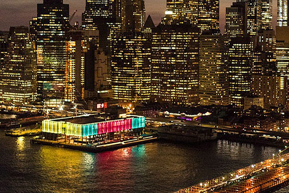 aerial shot of the seaport district and pier 17 lit up in yellow green and red