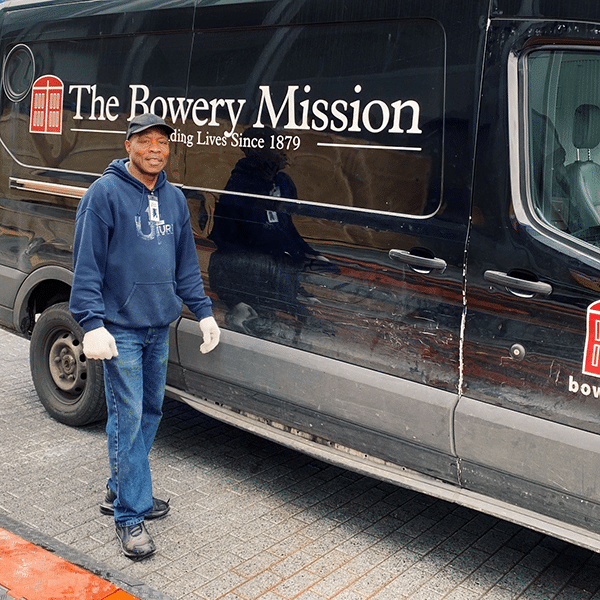 a bowery mission volunteer standing in front of a van