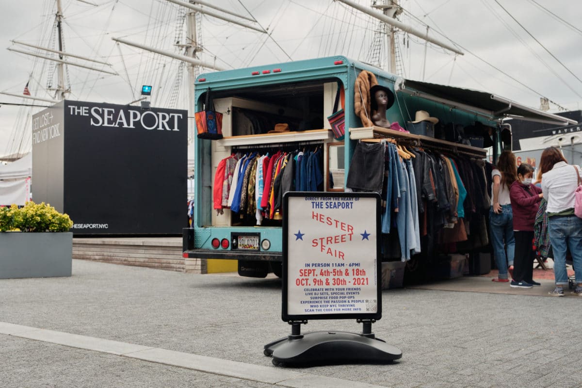 Hester Street Fair sign in front of a van selling vintage clothing and a sign for The Seaport