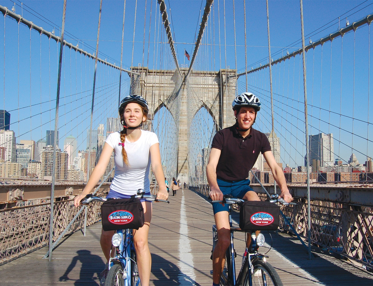 Man and woman on bikes crossing the Brooklyn Bridge