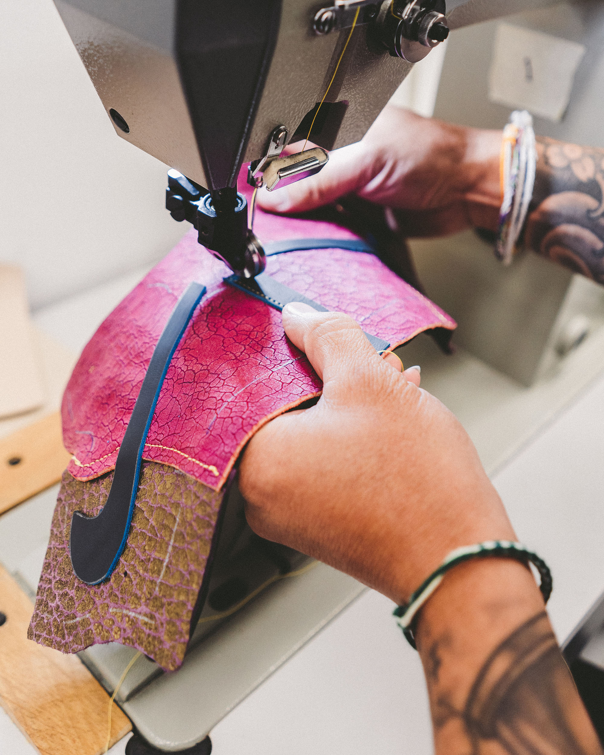 person sewing a Nike swoosh onto leather