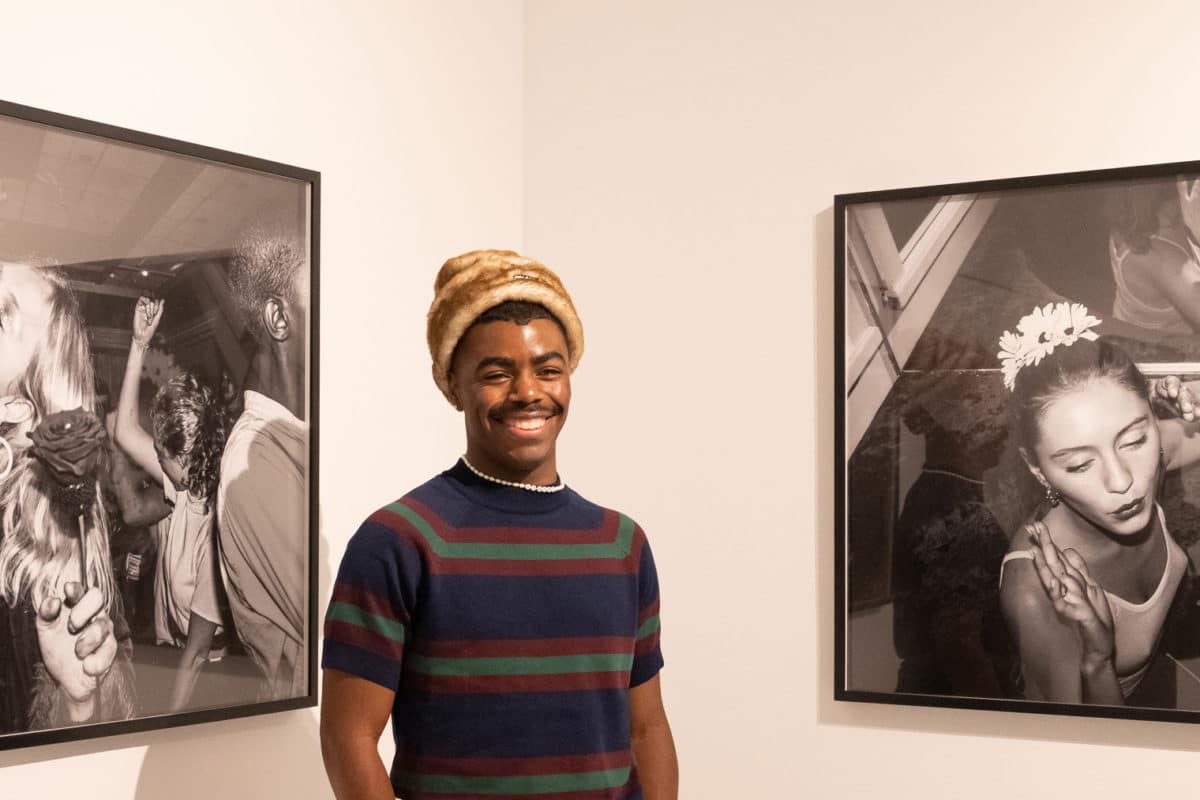 Tyrell Hampton posing with two black and white photographs at his exhibit Go Home at the SN37 Gallery at the Seaport in NYC