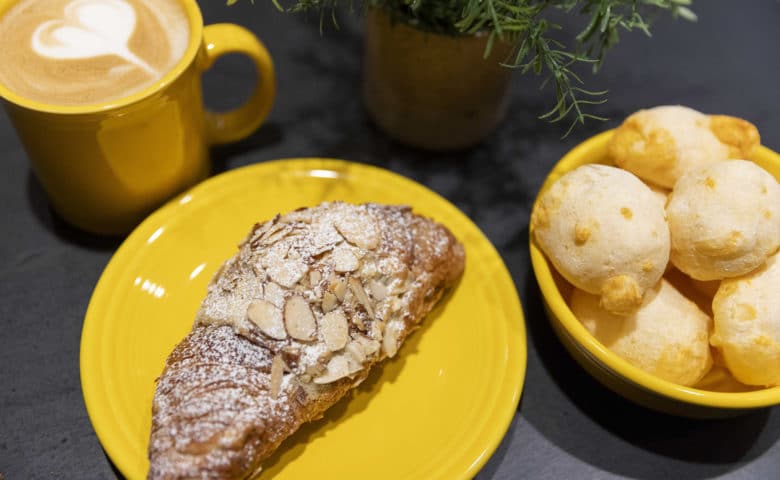 almond croissant, Brazilian cheese balls, and a latte with a foam heart