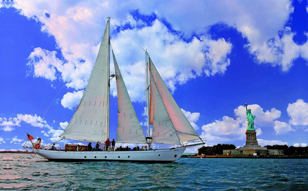 Shearwater sailboat by Manhattan by Sail on the water passing the Statue of Liberty