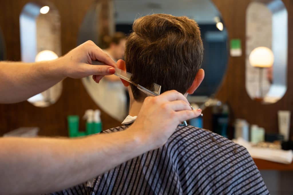 Hair stylist cutting a man's hair at the Fellow Barber shop
