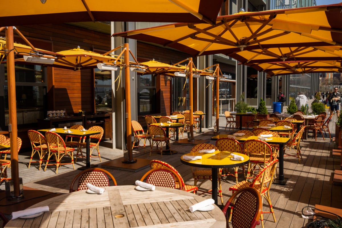 Outdoor tables, chairs, and umbrellas at Carne Mare on the deck at Pier 17