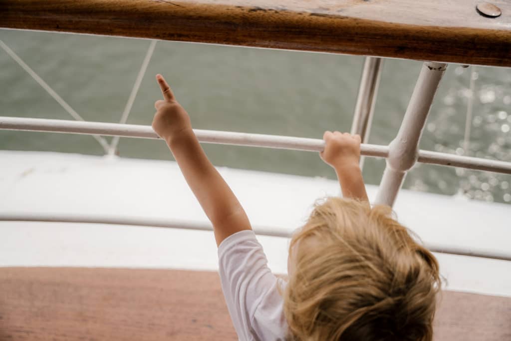 child on a sailboat pointing into the distance