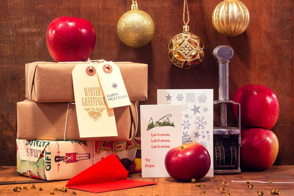 holiday display made of wrapped up boxes, apples, and gold Christmas tree ornaments