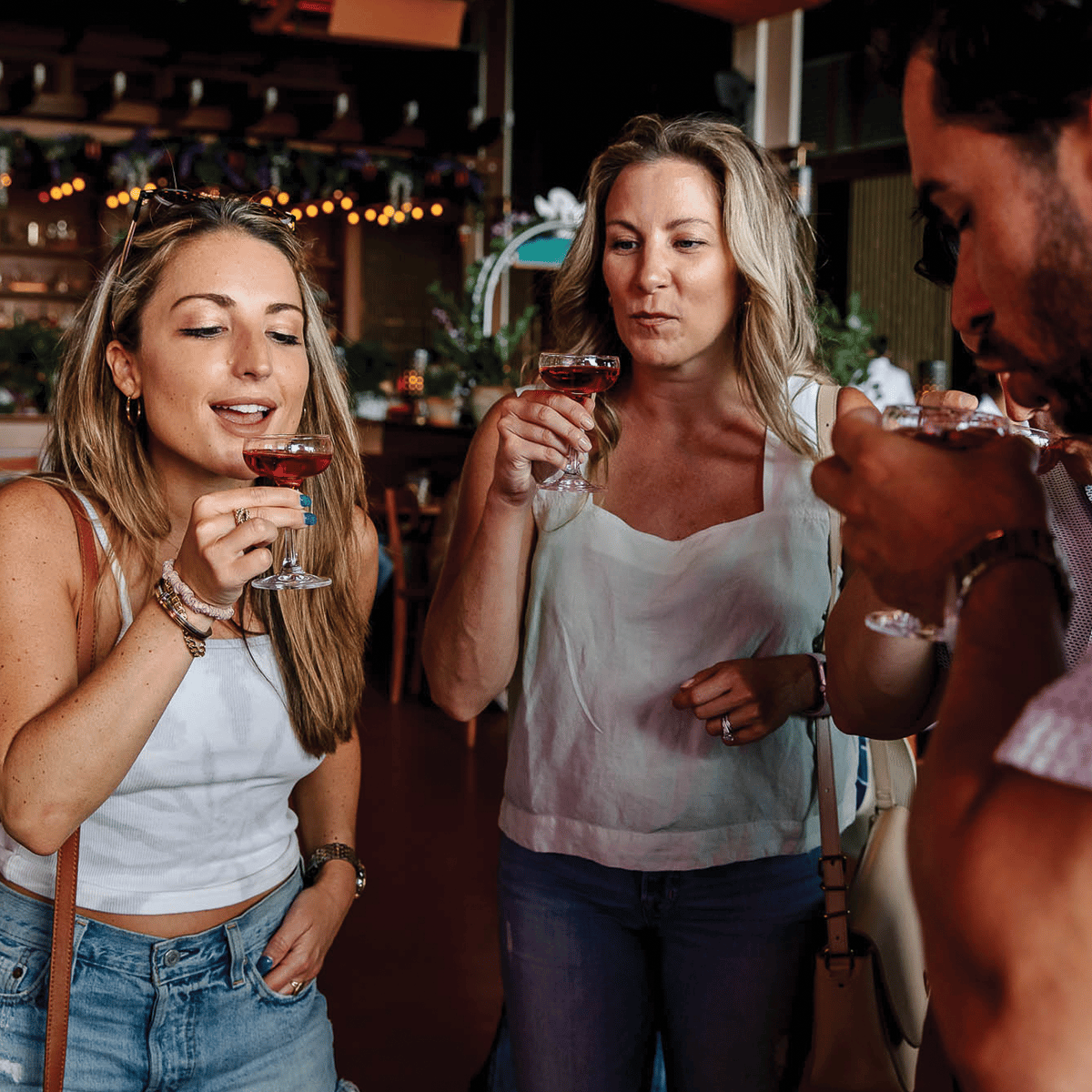 a group of three enjoying cocktails at a bar