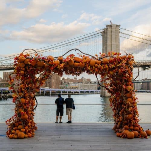 2 people standing under the Pumpkin Arch at Pier 17.