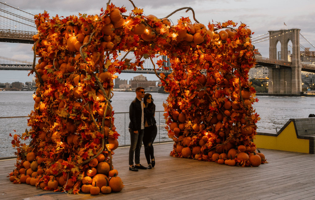A couple standing under Pumpkin Arch installation in the Seaport