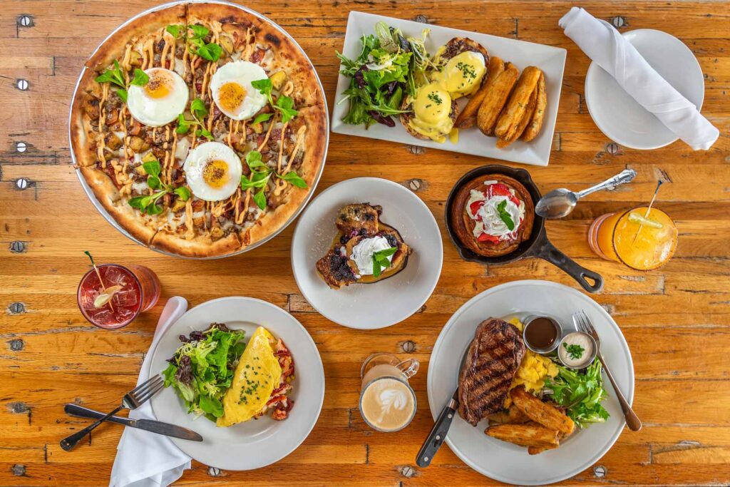 a spread of dishes on a wooden table at Industry Kitchen at the Seaport NYC