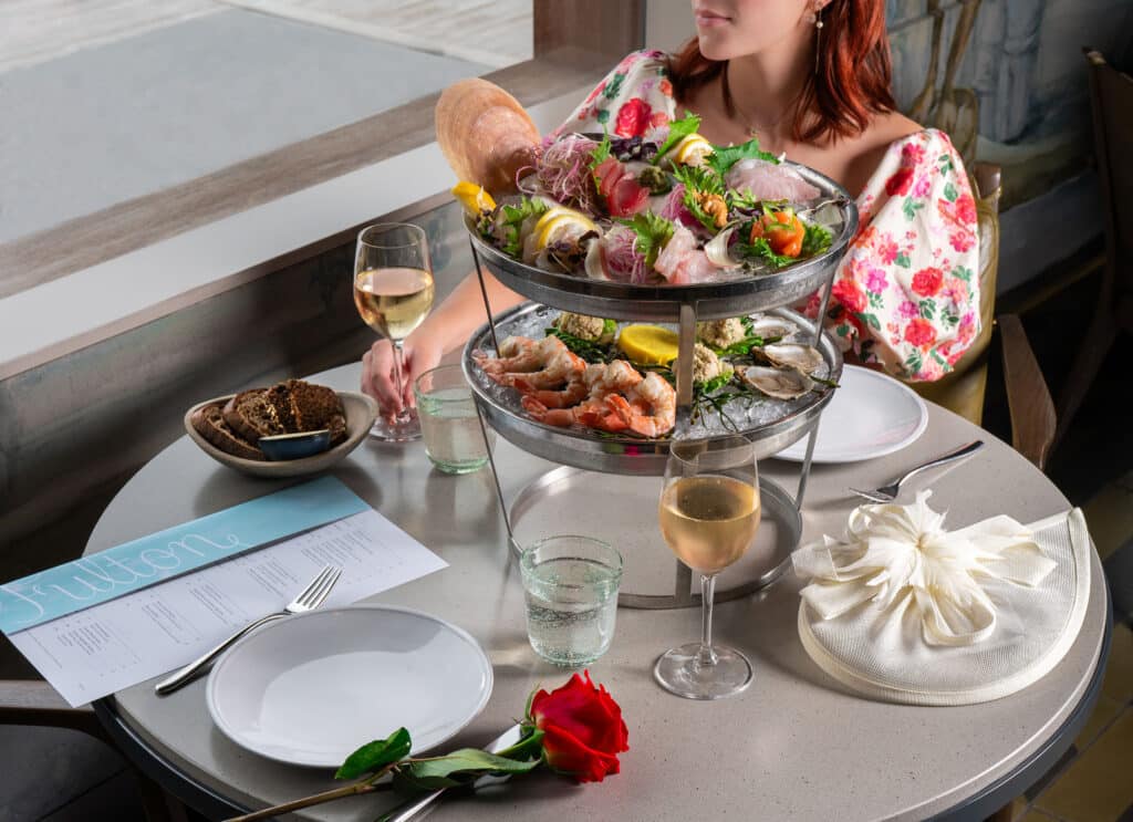 seafood plateau with a lady in a floral dress and a hat in the background