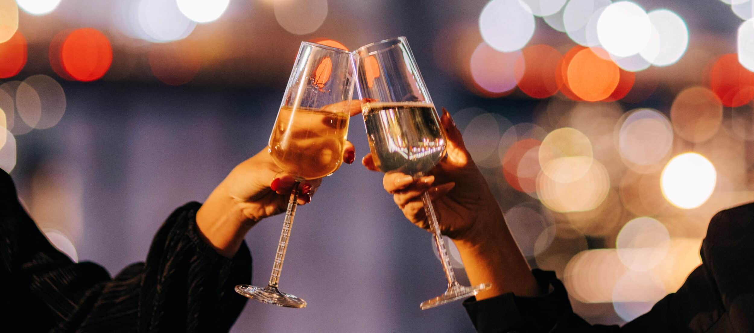 a couple toasts champagne in front of the brooklyn bridge