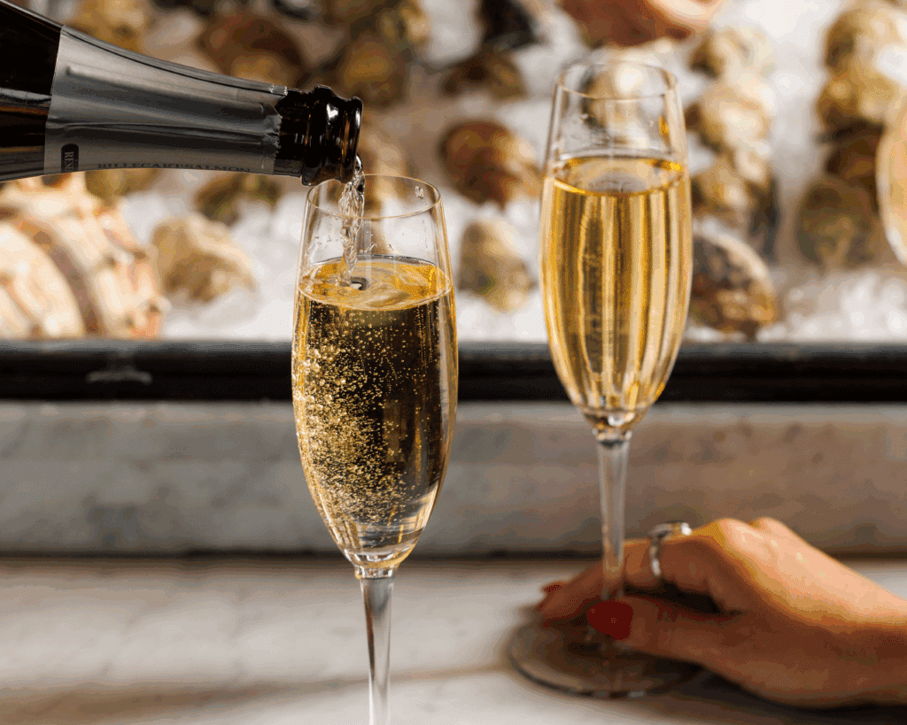 two glasses of champagne being pour at the fulton with oysters in the background