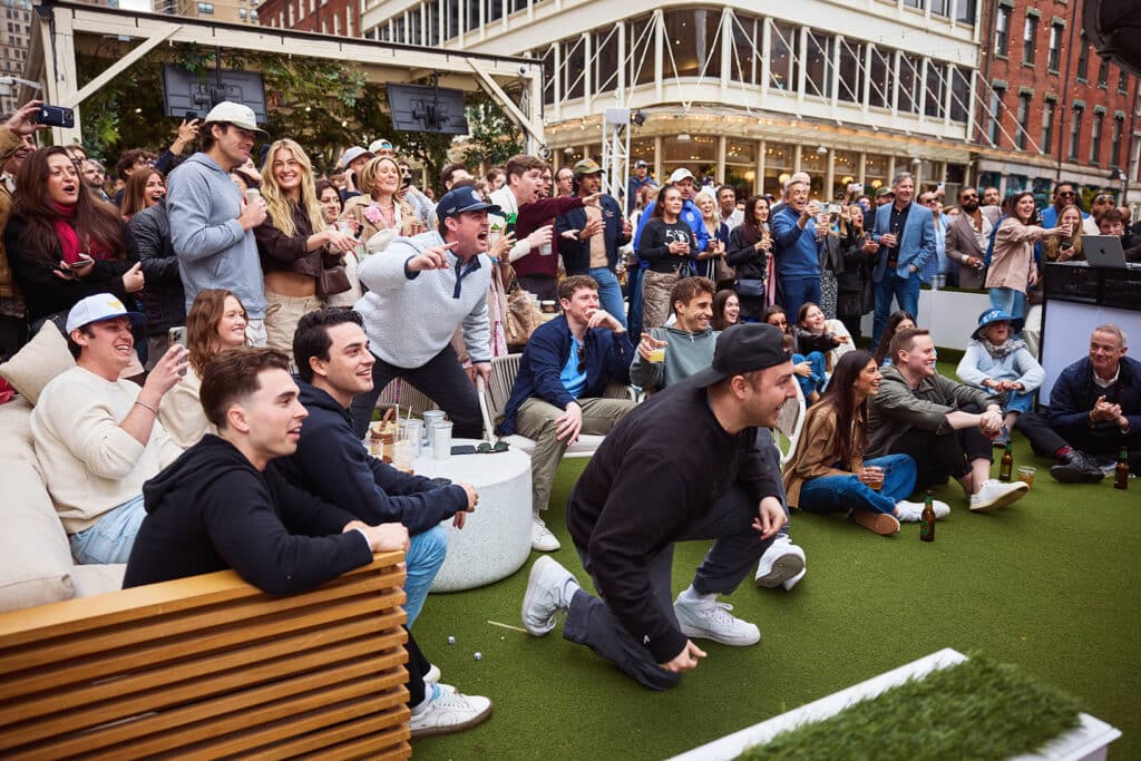 a group of young men cheer for an outdoor sports watch party at sadie's garden bar