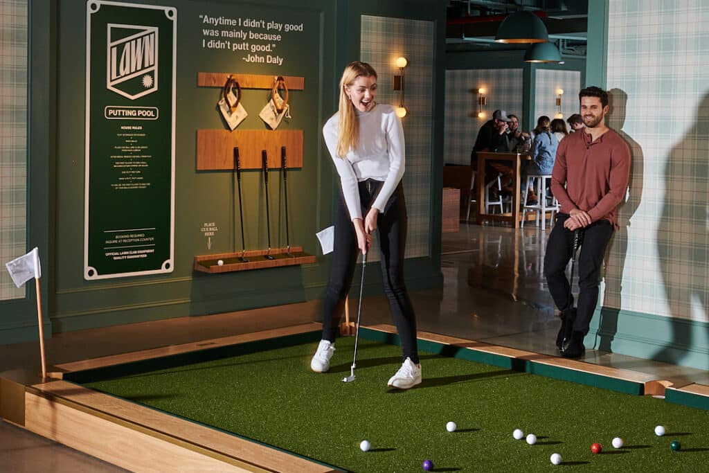 two young adults putting lawn billiards at lawn club