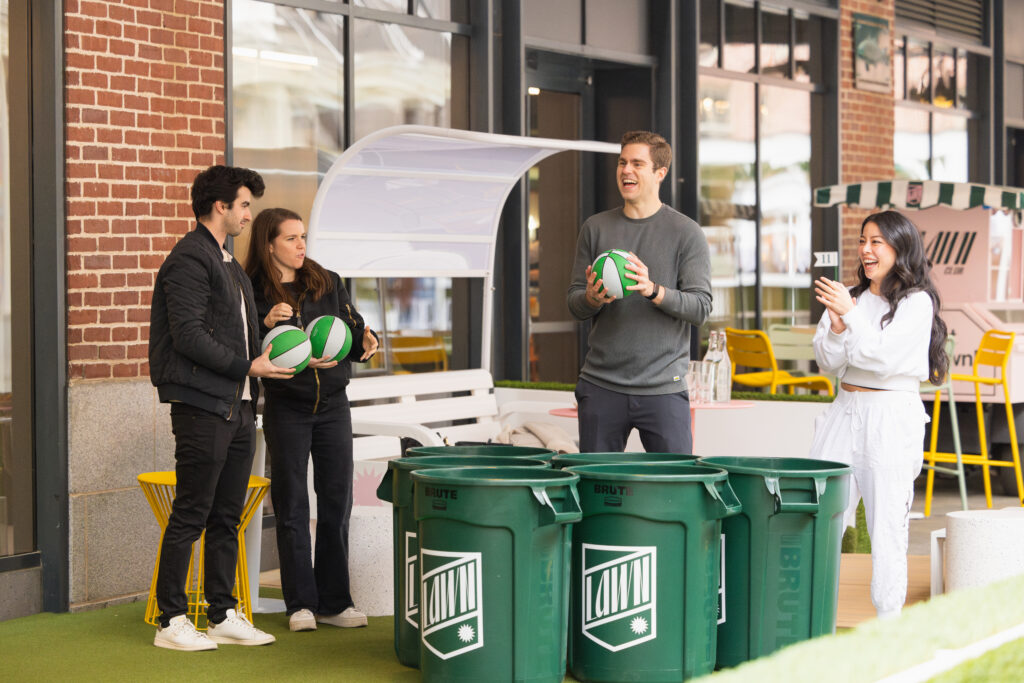 a group of young adults play giant pong at lawn club's outdoor terrace
