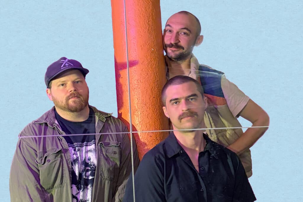 the band CS cleaners - three young men posing around an orange column